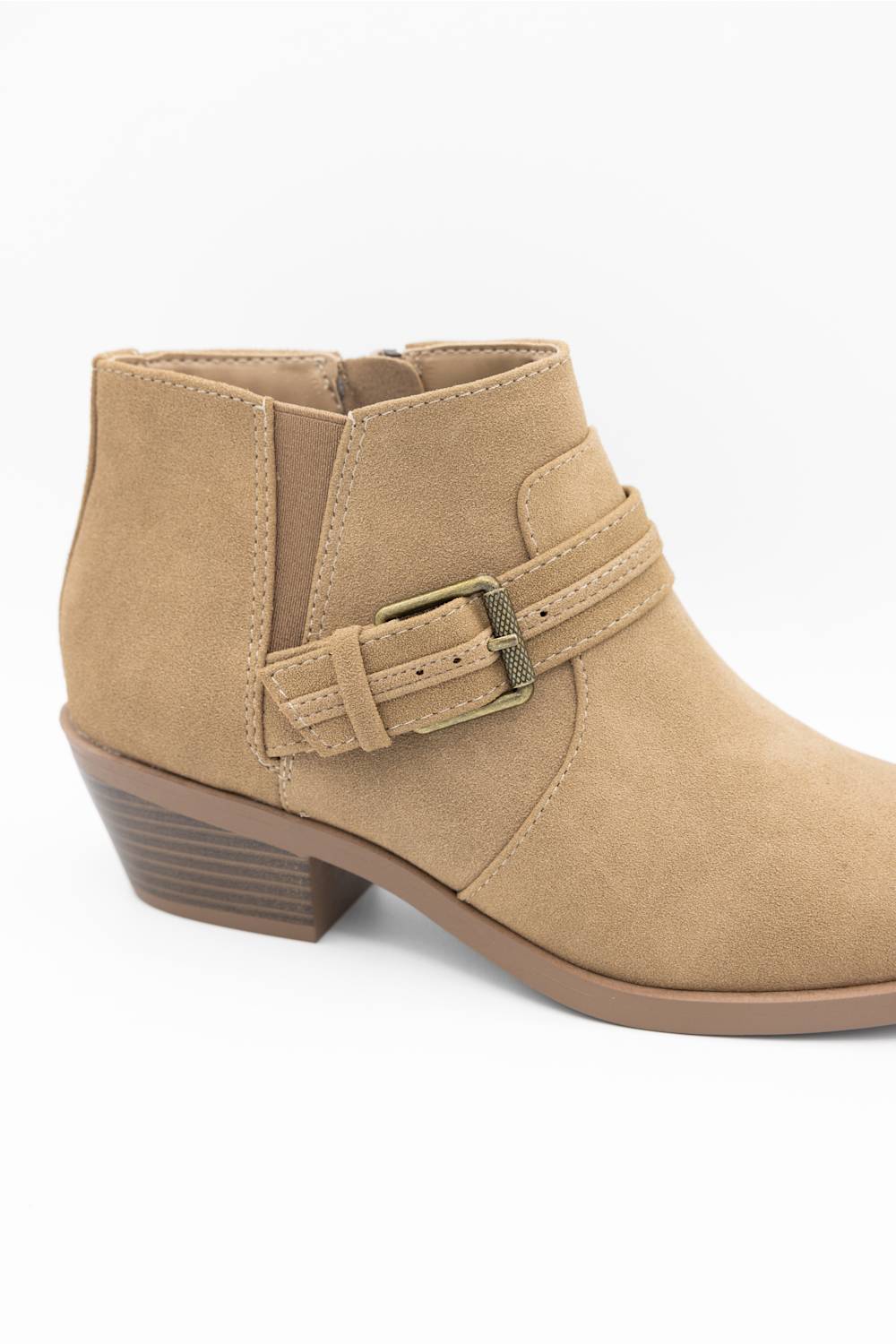 A tan suede ankle boot with a side buckle strap and a low stacked heel, shown from a side profile view on a white background.