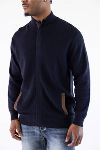 Man wearing a navy mock neck jacket standing against a white background
