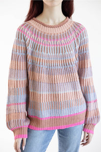 A woman wearing a chunky knit crewneck sweater with horizontal stripes in dusty pink, light blue, and bright pink, paired with light blue jeans against a plain white background.