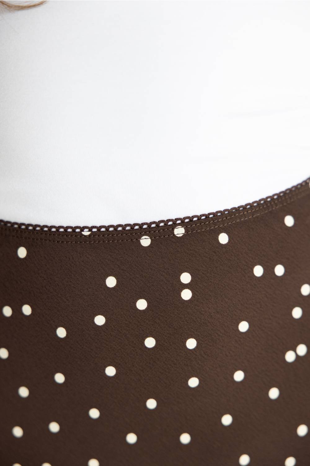 Close-up of a dark brown skirt with white polka dots and a delicate lace trim along the waistband.