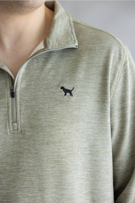 Close-up of a person wearing a light olive green quarter-zip pullover with a small black dog silhouette logo on the chest.