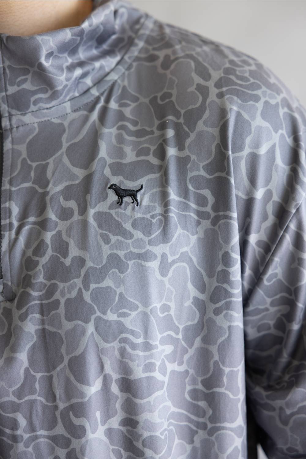 Close-up of a gray and white abstract patterned athletic top with a small black dog silhouette logo on the chest.