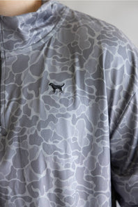 Close-up of a gray and white abstract patterned athletic top with a small black dog silhouette logo on the chest.