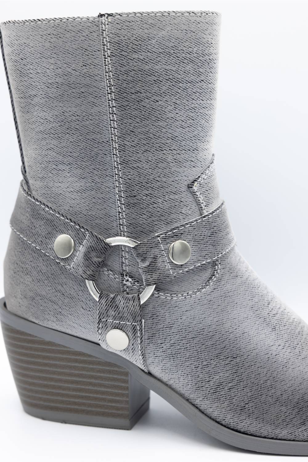 A gray faux-leather ankle boot with a textured grain, featuring a decorative strap with silver-tone rivets and a central ring detail, set against a plain light background.