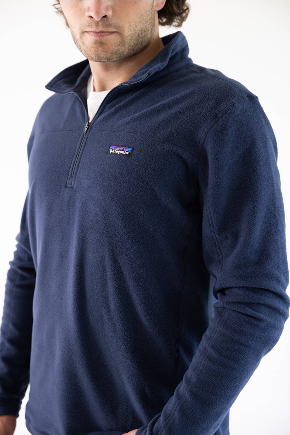 A man wearing a navy blue microfleece quarter zip pullover with a Patagonia logo on the upper left chest.