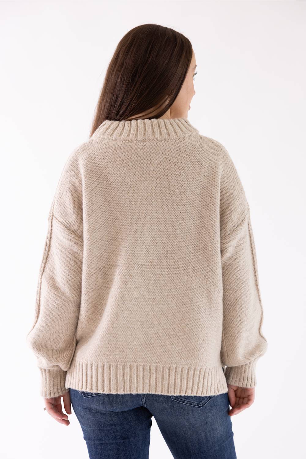 A woman modeling the Pink Rose Mock Neck Sweater in Heather Oatmeal, featuring a ribbed mock neck, drop shoulders, and long sleeves with ribbed cuffs, paired with dark-wash jeans.