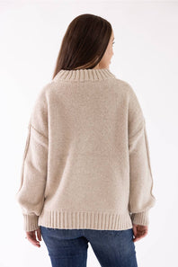 A woman modeling the Pink Rose Mock Neck Sweater in Heather Oatmeal, featuring a ribbed mock neck, drop shoulders, and long sleeves with ribbed cuffs, paired with dark-wash jeans.
