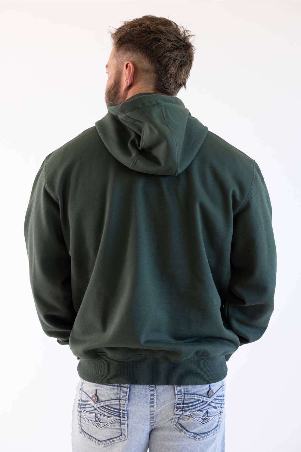 Back view of a model wearing a men's dark green forestry hoodie paired with light wash denim jeans.