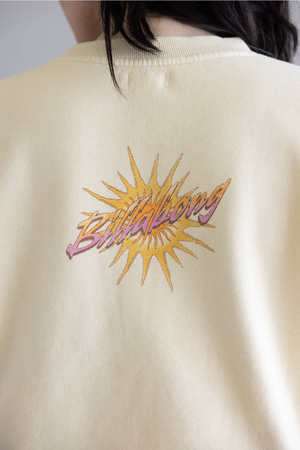 Beige sweatshirt with a colorful 'Billabong' logo on the back
