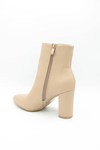 A beige ankle boot with a block heel and side zipper, shown from a rear three-quarter angle on a white background.