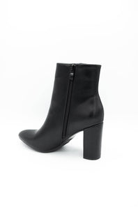 A black leather ankle boot with a block heel and side zipper, shown from a rear three-quarter angle on a white background.