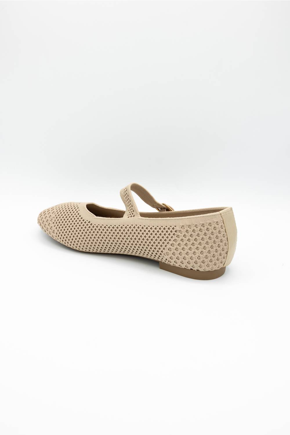A single beige flat shoe with a textured, perforated upper and a matching ankle strap, shown from a side-rear angle on a white background.