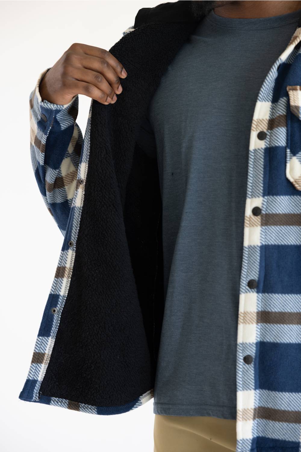 A close-up of a person wearing a blue, white, and brown plaid flannel shirt with a black fleece lining, layered over a slate blue t-shirt.