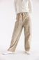 A person wearing beige wide-leg cargo pants with a drawstring waist, paired with a cream cable-knit sweater and white sneakers, shown from the chest down against a plain white studio background.