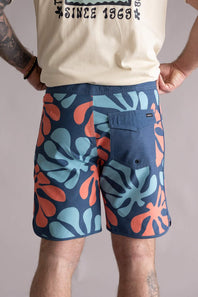 Back view of a person wearing colorful floral-patterned shorts on a plain background. The shorts are named that Quiksilver Sol Tiles 19" Boardshorts for Men in Dark Denim.