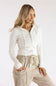 Three-quarter view of a model wearing a Pink Rose blizzard white cable-knit full-zip sweater hoodie styled with beige drawstring utility cargo pants against a plain backdrop.