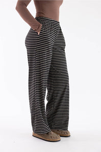 A person wearing loose, wide-leg striped pants with a brown long-sleeve top and brown shoes, shown from the waist down against a plain white studio background.