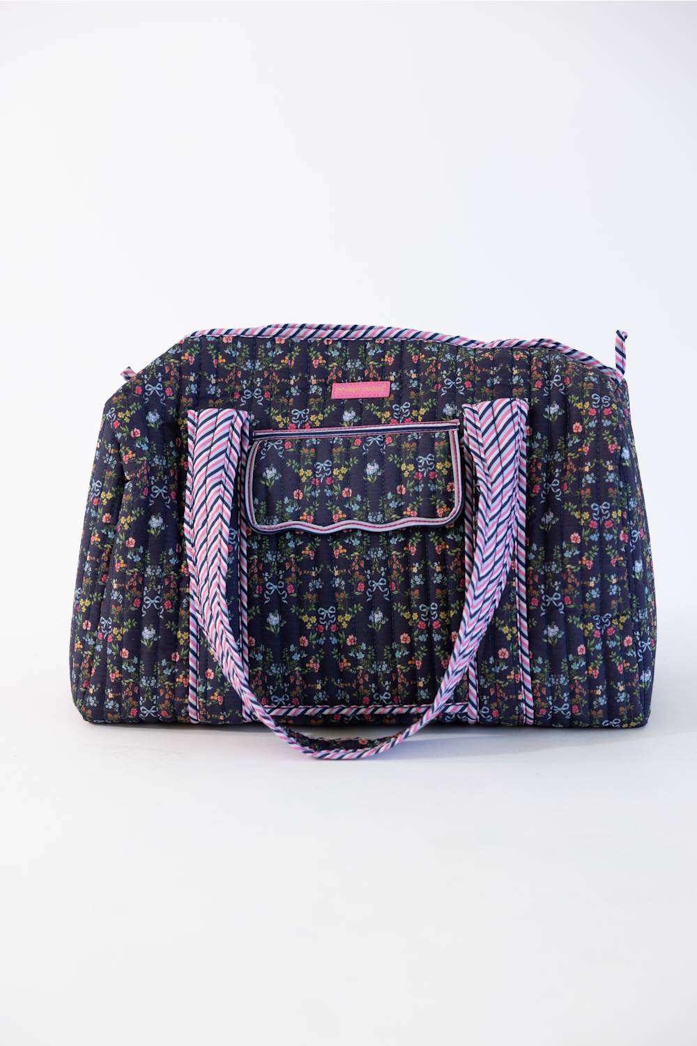 A floral print duffel bag with purple braided handles and a matching zippered pocket, shown against a plain white background.