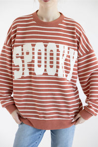 Women wearing dusty mauve sweatshirt with white horizontal stripes, SPOOKY screen printed on front and blue denim jeans on a basic background