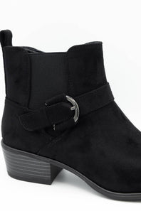 A black suede ankle boot with a side strap and silver buckle, shown from a three-quarters angle on a white background.