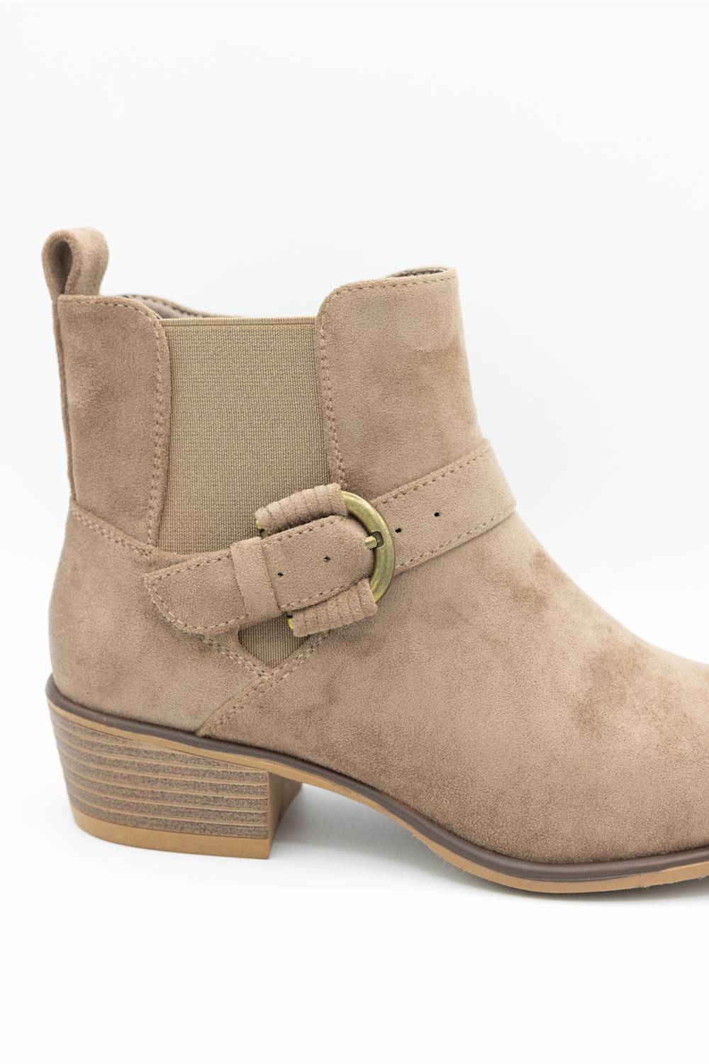A beige suede ankle boot with a matching elastic side strap and a gold-tone buckle, shown from a side profile on a white background.