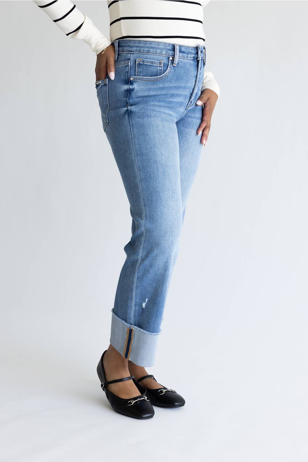 Woman wearing striped shirt with straight leg jeans and cuffed leg. 