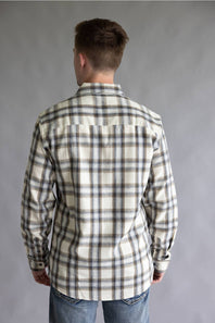 Back view of a male model wearing the Split Flannel Shirt for Men in Grey Ecru, showcasing the beige, gray, and brown plaid pattern across the back, straight yoke, long sleeves, and rounded hem against a neutral gray background.