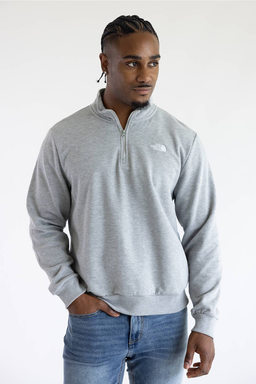 A man wearing a heather grey quarter zip The North Face men's sweatshirt with a white logo on the upper left chest.