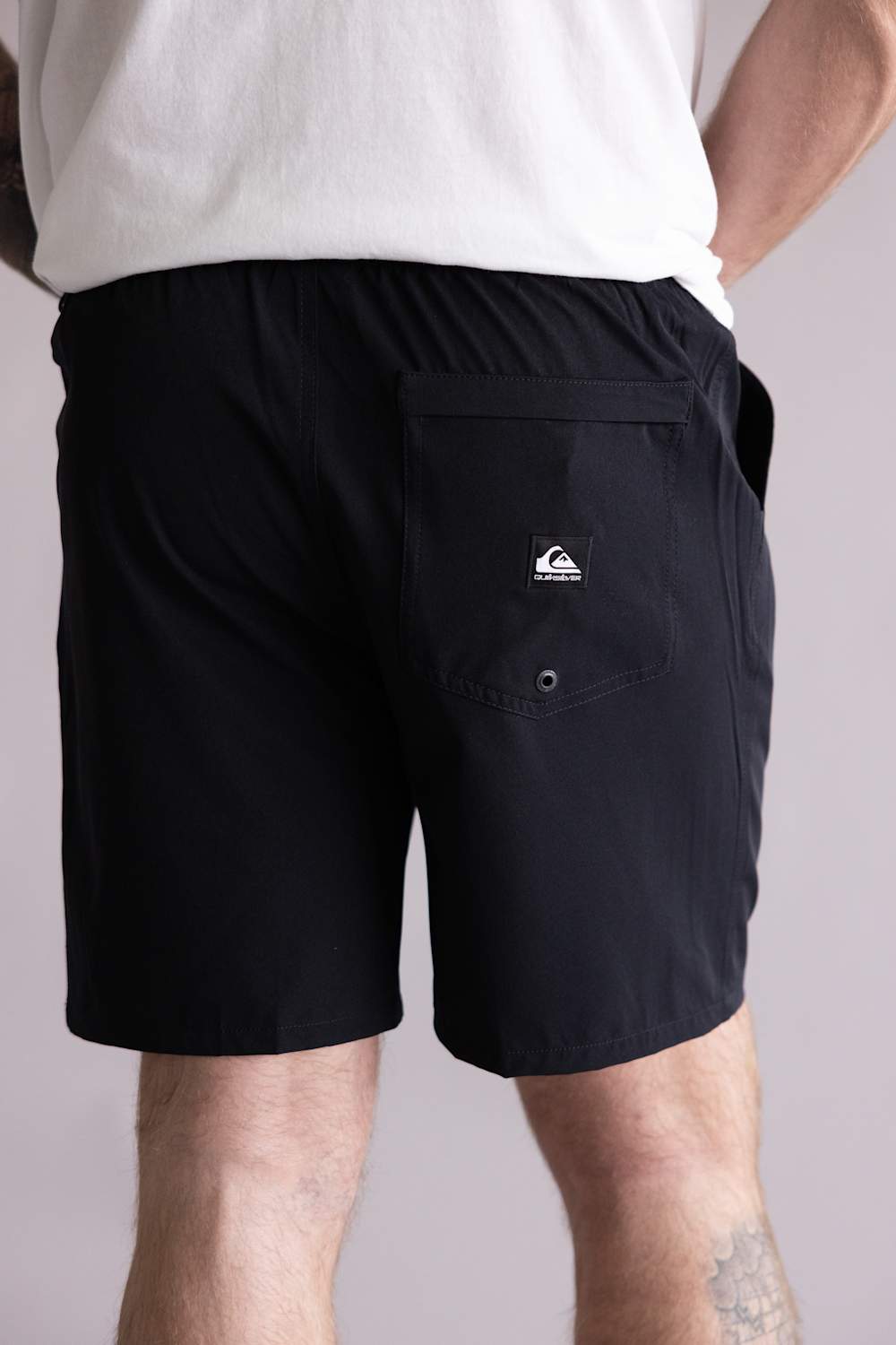 Back view of a person wearing black shorts with a logo on a plain background. The shorts are the Quiksilver Union Amphibian 20" Hybrid Shorts for Men in Black.