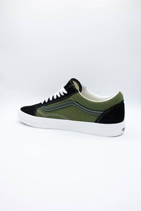 A low-top skate shoe in black and olive green suede with a white rubber sole, shown from a side profile view against a white studio background.