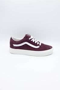 A single Vans low-top sneaker in dark burgundy suede with white laces and a white rubber side stripe and sole, shown on a light gray studio background.