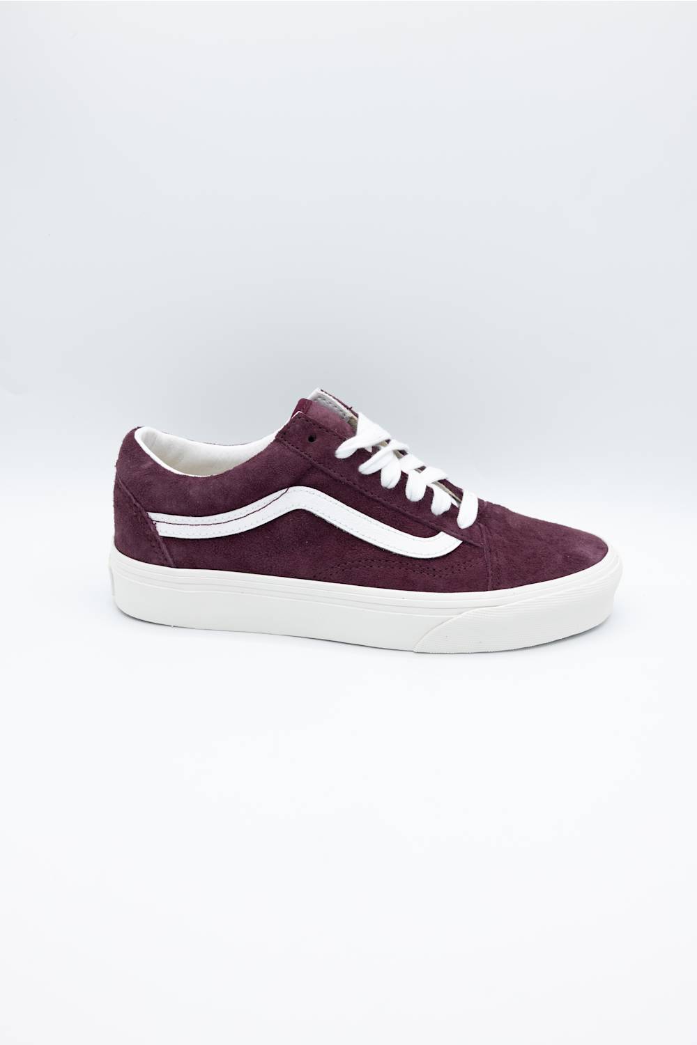 A single Vans low-top sneaker in dark burgundy suede with white laces and a white rubber side stripe and sole, shown on a light gray studio background.