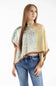 Woman modeling a green and yellow paisley patchwork off-the-shoulder scarf poncho top paired with denim jeans.