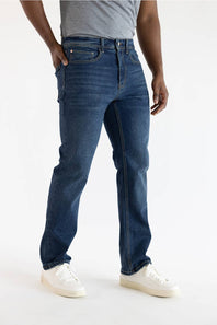 A person wearing dark blue denim jeans, a gray t-shirt, and white sneakers, shown from the waist down against a plain white studio background.