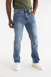 A person wearing light blue slim-fit denim jeans with a faded wash, paired with an olive green t-shirt and white sneakers, shown from the waist down on a white studio background.