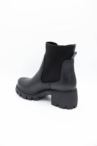 A single black ankle boot with a ribbed elastic side panel and a chunky lug sole, photographed on a clean white background.