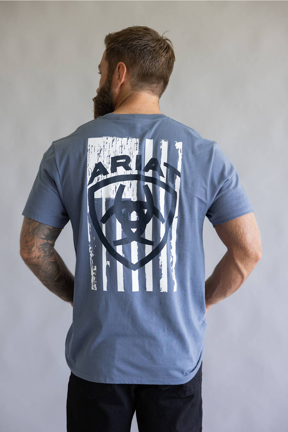 Close-up of a white distressed American flag graphic printed on the chest of a slate blue t-shirt.