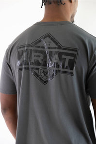 A man wearing a dark gray t-shirt, viewed from the back. The shirt features a large distressed black graphic on the back with the word 'Ariat' inside a diamond outline and a biohazard symbol below it.