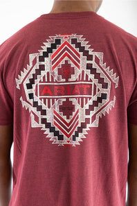 A close-up of a person wearing a heathered red t-shirt, showing the back of the shirt with a large distressed white and red geometric Southwestern-style graphic featuring the brand name 'ARIAT'.