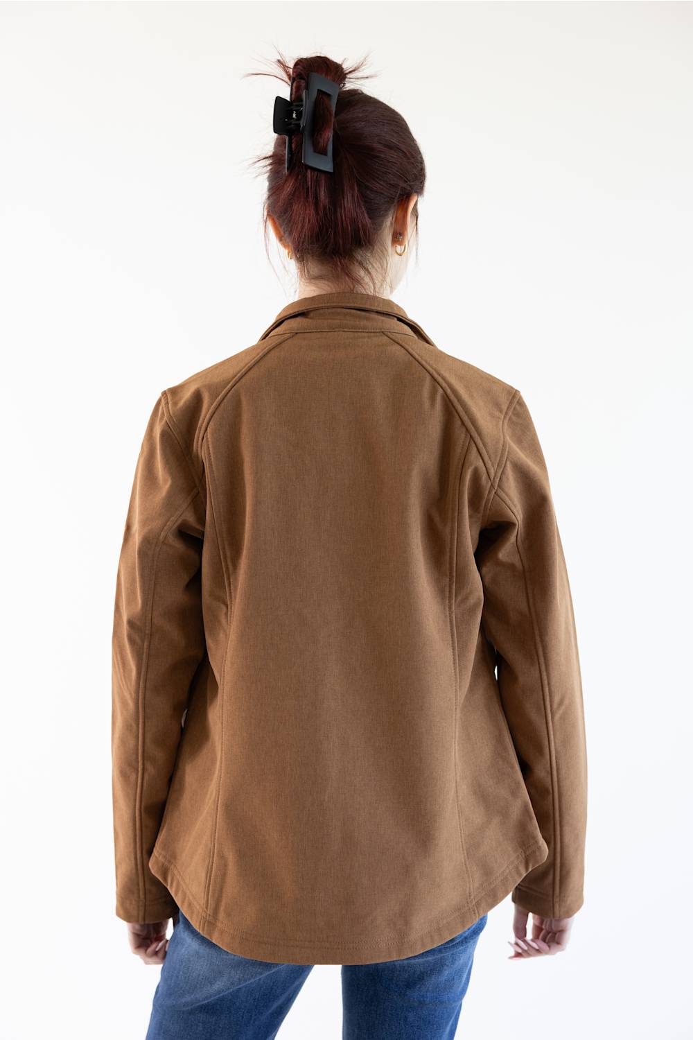 A person viewed from the back wearing a brown jacket and blue jeans against a plain white studio background.