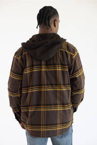 A man viewed from behind wearing a brown hooded jacket with a yellow and black plaid pattern, paired with blue jeans, against a plain white background.