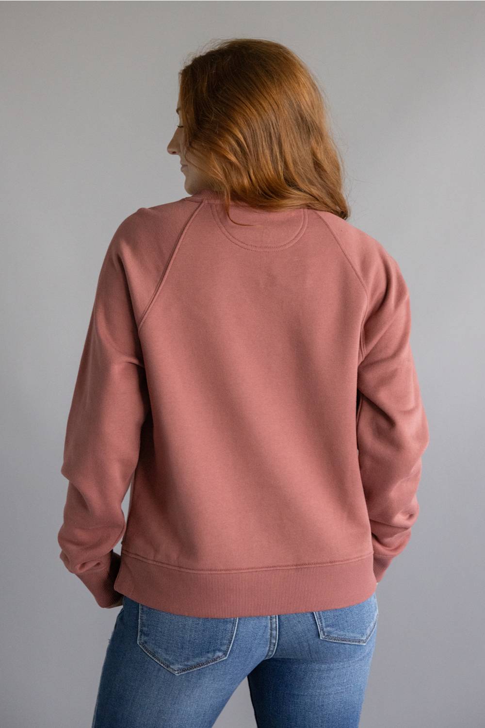 Dark red colored sweatshirt with orange Carhartt cursive letters on chest 