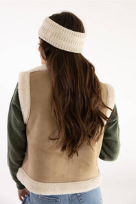 Carhartt Satin Lined Knit Headband in Oat Milk worn from behind with long brown hair, a fleece vest, and olive long-sleeve top