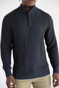 A man wearing a dark brown ribbed knit quarter-placket sweater with blue cable knit accents down the front, paired with khaki pants.