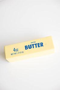 Squishy toy butter stick with yellow wrapper and blue text on a white background