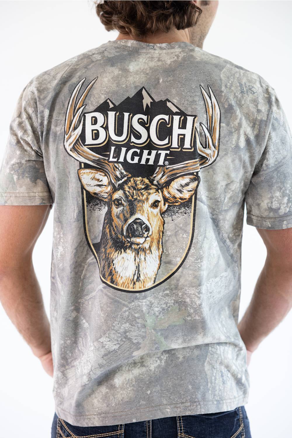 Back view of a man wearing a camo JEDCo t-shirt featuring a large Busch Light logo and a whitetail deer graphic printed on the back.