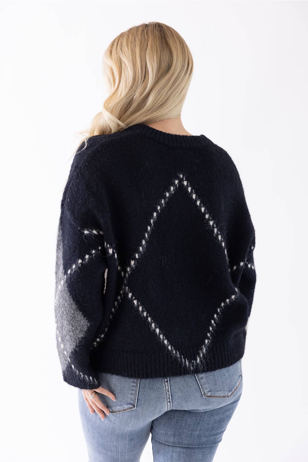 back view of a blonde woman modeling a stylish argyle sweater 