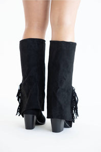 Black suede knee-high boots with a block heel, shown on a model's legs against a plain white studio background.