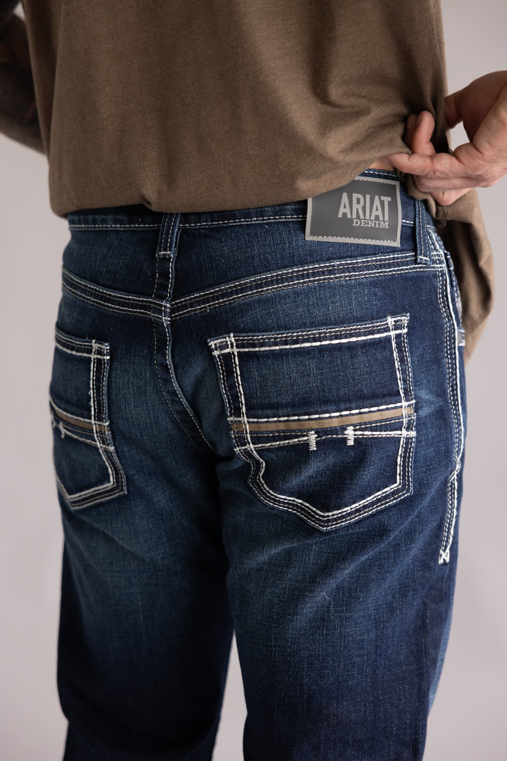 Ariat M5 Slim Stretch Coltrane Straight Leg Jeans for Men; Person wearing blue jeans with Ariat branding on a plain background