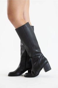 Black leather knee-high boots with a block heel, shown on a model's legs against a plain white studio background.